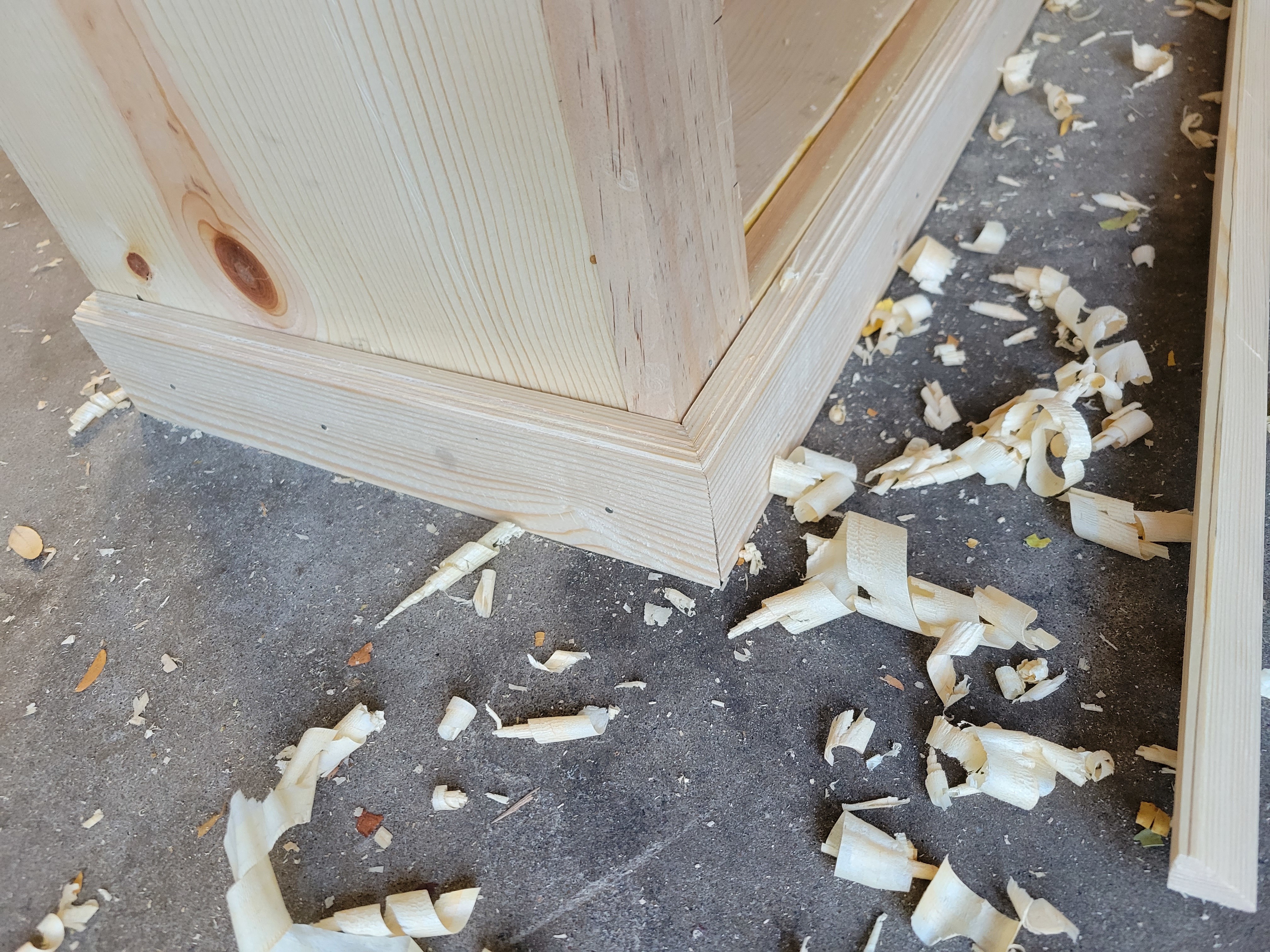 a closeup picture of the corner of an unfinished pine cabinet, where you can see stairstep molding has been attached